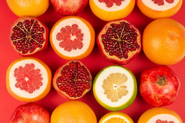 Obraz na płótnie Canvas Grapefruit, orange, pomegranate, citrus sweetie on red background.