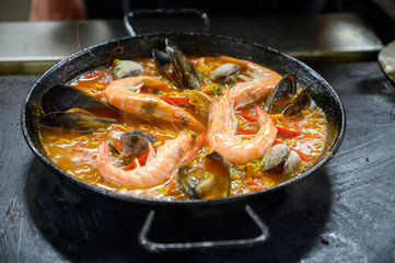 Spanish cuisine, man making paella, famous dish with rice and seafood from Valencia