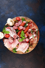 Naklejka na ściany i meble Food tray with delicious salami, pieces of sliced prosciutto crudo, sausage and basil. Meat platter