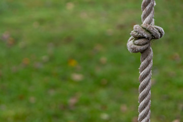 Starkes Hanfseil als Kletterseil mit Knoten im Garten als Spielplatz für Kinder und Jugendliche als Geschicklichkeitstraining und Bewegungsspiel mit frischer Luft draußen auf der Wiese