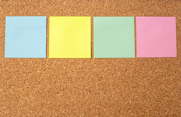 Cork board with several colorful blank notes with pins