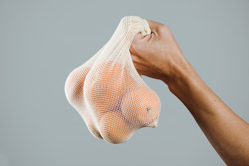 man and reusable mesh bag with oranges.