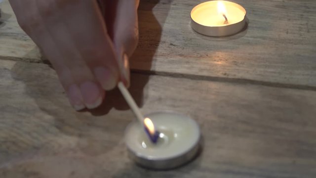 Fortuneteller's female hand, lights candles on the background of fortune-telling cards.