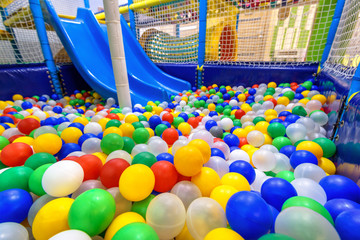 Kids playground indoor. Panoramic view inside the dry pool with colorful balls and slide. Nice plastic gym for activity in playroom.
