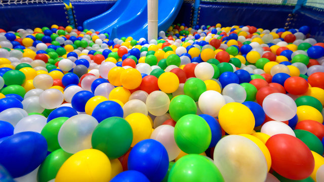 Playground for sport and play in kindergarten. Panoramic view inside the plastic dry pool with many colorful balls and slide.