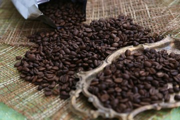 Vintage tray with large grains of special roasting coffee and bag packing for coffee on the table