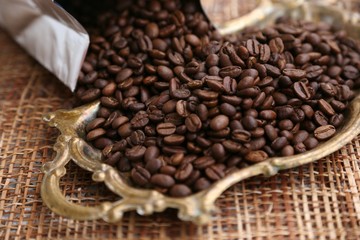 Coffee in grains is poured on the metal tray
