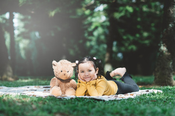 little asian girl lying down beside her teddy bear. Concept of childhood and tenderness