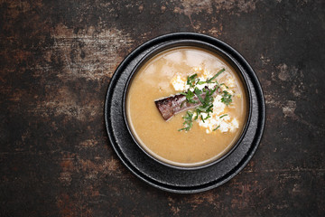 Creamy soup with toppings and herbs. Food, ready dish on a dark background. Suggestion of serving the dish