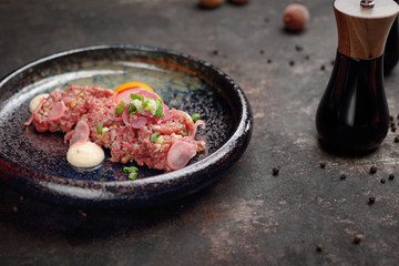 Beef sirloin tartare with egg yolk. Food, ready dish on a dark background. Suggestion of serving the dish.