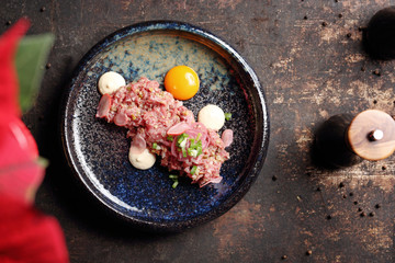 Raw chopped beef tenderloin served with yolks. Food, ready dish on a dark background. Suggestion of serving the dish.