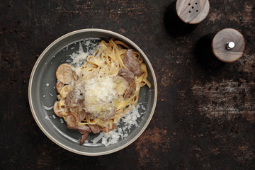 Tagliatelle with porcini mushrooms and tenderloin in a cream sauce. Food, ready dish on a dark background. Suggestion of serving the dish.