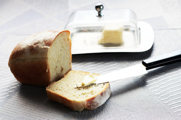 A slice of fresh bread with butter and knife