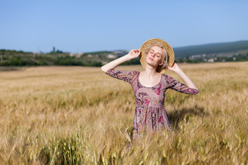 portrait of a beautiful fashionable blonde woman in a hat in a field of ripe wheat