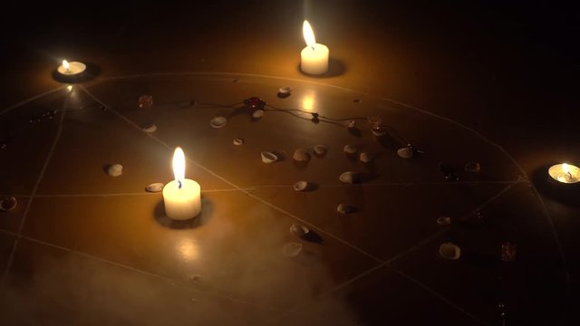 shells and stones, white candles burn in the pentagram on a wooden floor. Magical ritual with occult, evil and esoteric symbols. There is smoke, steam.