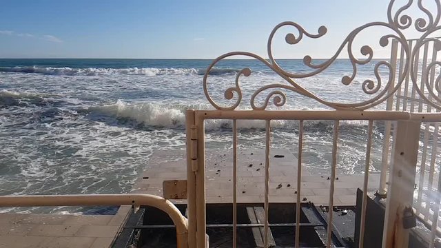 Alassio, Italia. Cancello su spiaggia con mare ondoso