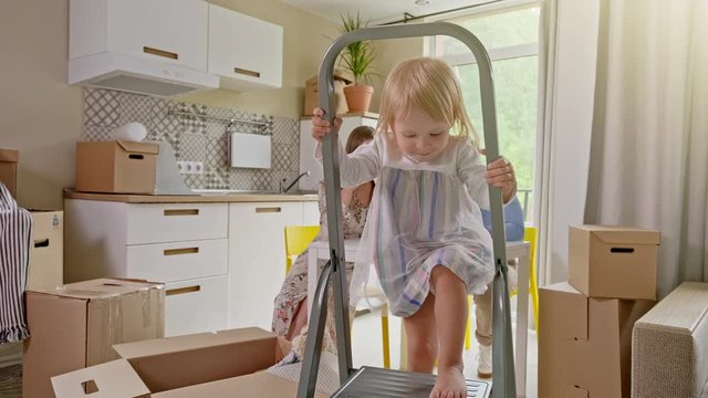 Active Family Group Move in Rent Real Estate. Positive Looking at Relocating or Unpacking of Carton Pack by Playful Family. ittle girl climbs the stairs and looks at the camera. Enjoying Life