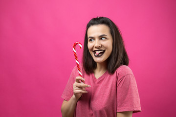 Portrait of lovely sweet beautiful cheerful woman with straight brown hair trying to bite red candy cane christmas.