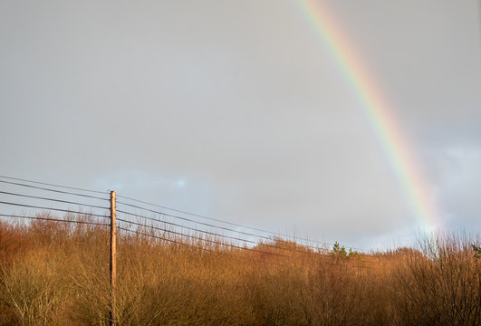 Power landline in Ireland with rainbow in the background