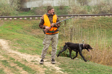 Hunting period, autumn season open. A hunter with a gun in his hands in hunting clothes in the...