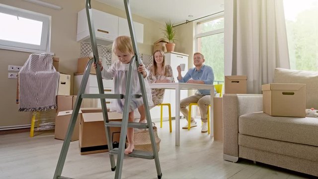Active Family Group Move in Rent Real Estate. Positive Looking at Relocating or Unpacking of Carton Pack by Playful Family. ittle girl climbs the stairs and looks at the camera. Enjoying Life