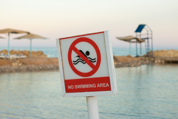 No swimming area sign on the sea beach. Crossed out floating person.