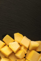 heap of pineapple cube slices on black background