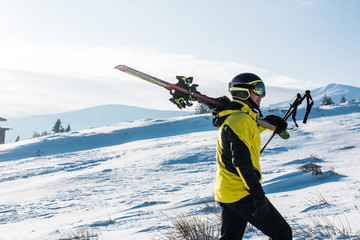 Fototapeta na wymiar Side view of skier walking with sticks in mountains