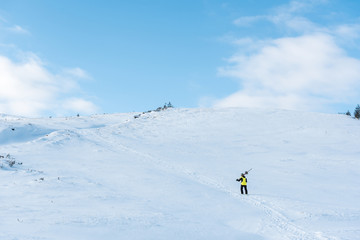 Naklejka na ściany i meble sportsman in helmet walking with ski sticks on white snow in mountains