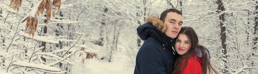 The guy and the girl have a rest in the winter woods. Husband and wife in the snow. Young couple walking in winter park	