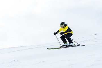 Fototapeta na wymiar sportsman in helmet and goggles skiing on slope in winter
