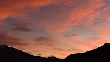 Tramonto con nuvole arancioni, rosse e rosa con giochi di luce incredibili