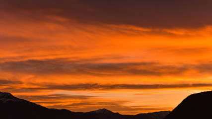 Tramonto con nuvole arancioni, rosse e rosa con giochi di luce incredibili