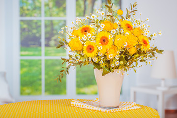 bouquet of yellow flowers in vase on wooden table
