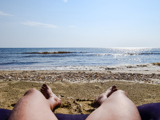 The legs of a man on a beach background. A man lies on an amatra