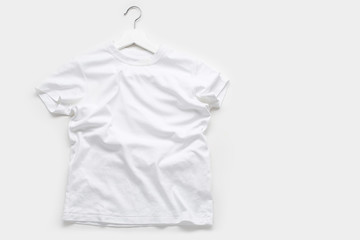 Flatlay with white t-shirt on white hanger on white background.