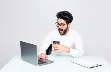 Fototapeta na wymiar Handsome businessman drinking coffee in office while typing on laptop