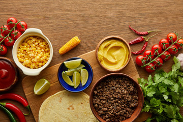 Top view of tortillas with fresh ingredients on wooden background