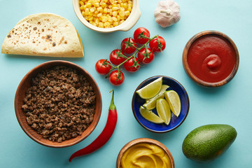 Top view of fresh ingredients for taco with meat on blue background