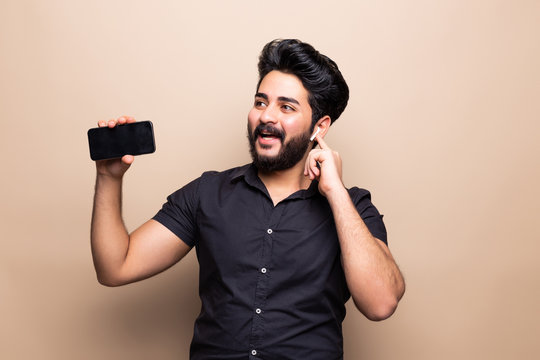 Young handsome man hold telephone in arms make take selfie isolated on beige background