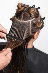 hairstylist  applying mask to hair of her client in beauty hair salon. the process of keratin straightening hair.