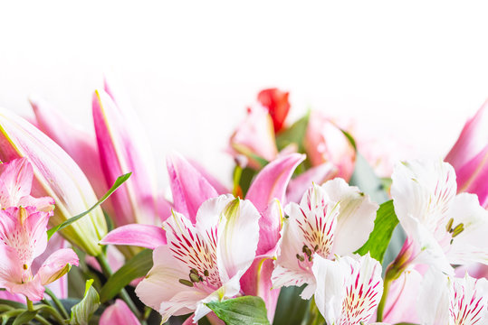 Bouquet of white alstromeria flowers and pink lilies close-up on a white background. Floral spring background with free space for text, copy space. Composition with beautiful blooming flowers.