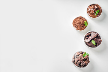 Different conditions of cocoa. Various cocoa - beans, beans, ground, crushed cocoa powder, chocolate paste, chocolate pieces and hot chocolate in a cup. In small bowls, white background above