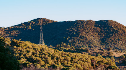 Power tower in the middle of the mountains and vegetation.