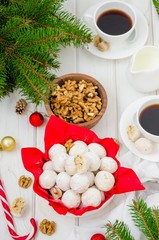 Homemade snowballs cookies with walnuts in icing sugar in a bowl on a white wooden background. Dessert for Christmas and New Year. Vertical orientation. Top view.