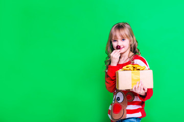 Beautiful blonde girl child stands with gifts on green background. Holidays, sale concept.