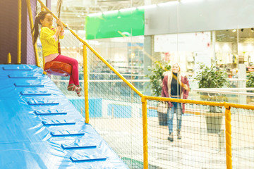 Naklejka premium Adorable Little girl laughing happily, riding upside down on a bungee swing on the playground in yellow. Happiness, freedom, enjoyment, health.