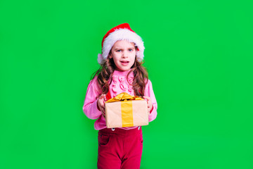 Beautiful girl child with brown hair stands with gifts on a green background. Holidays, the concept of sale.
