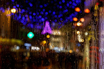 City view with Christmas lights through a window on a rainy day.