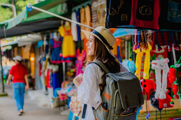 Fototapeta na wymiar A young traveler smiles in a gift shop on the Doi Pui landmark, Chiang Mai, with a backpack carrying a map on vacation. Relaxation concept Travel ideas